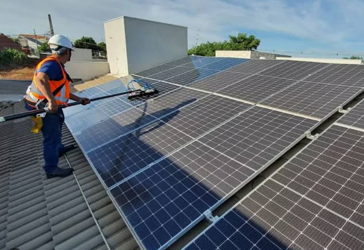 Profissional lavando placas solares no telhado